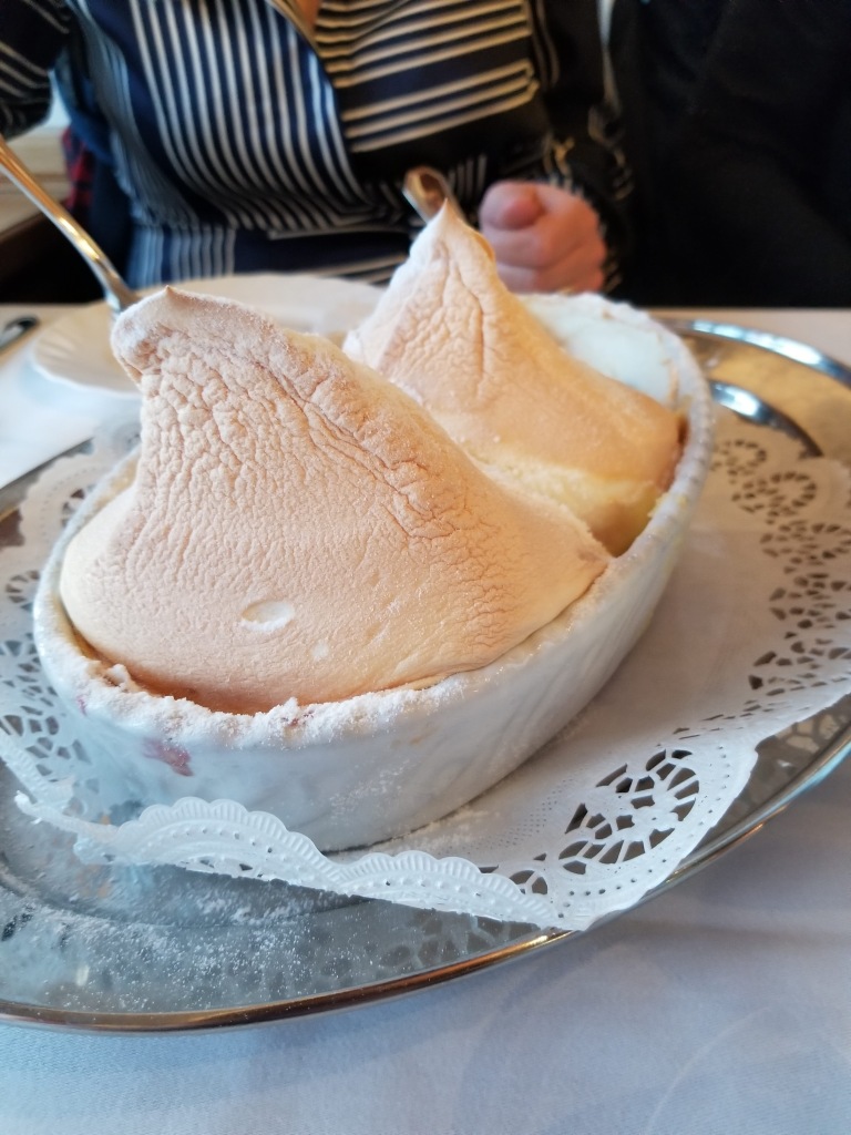 A puffy, cream colored, meringue soufflé dish called a Knockerl in a white ceramic dish